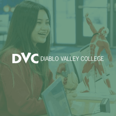 student talking with an advisor with a human figure model on the table between them green overlay with the DVC logo on top